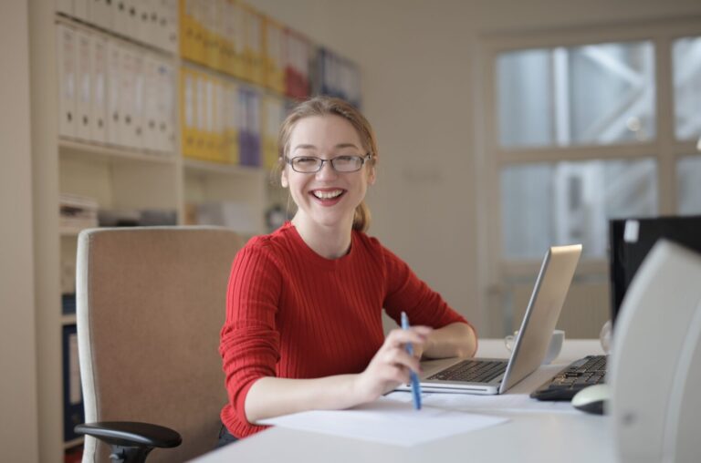 An office woman smiling and happily working at her desk