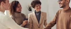 Diverse group of young adults shaking hands in an office environment, depicting teamwork and collaboration